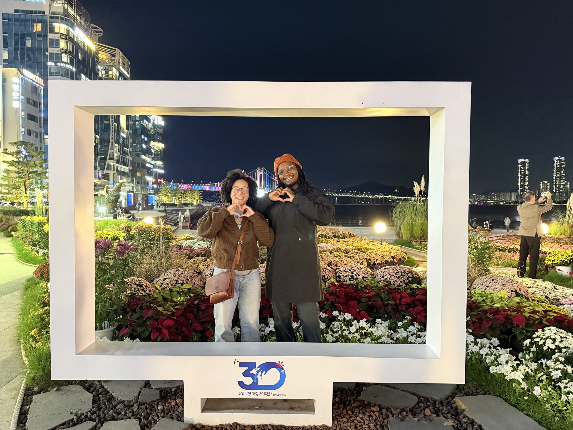 Magen and Thomas posing in a lit photo frame at night